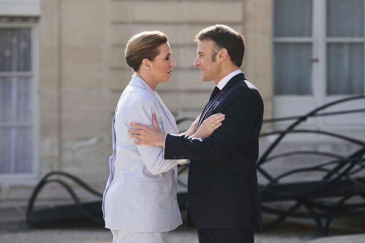 To personer i formelle antrekk står vendt mot hverandre utenfor, de har øyekontakt og holder hverandre i armene i en samtale.