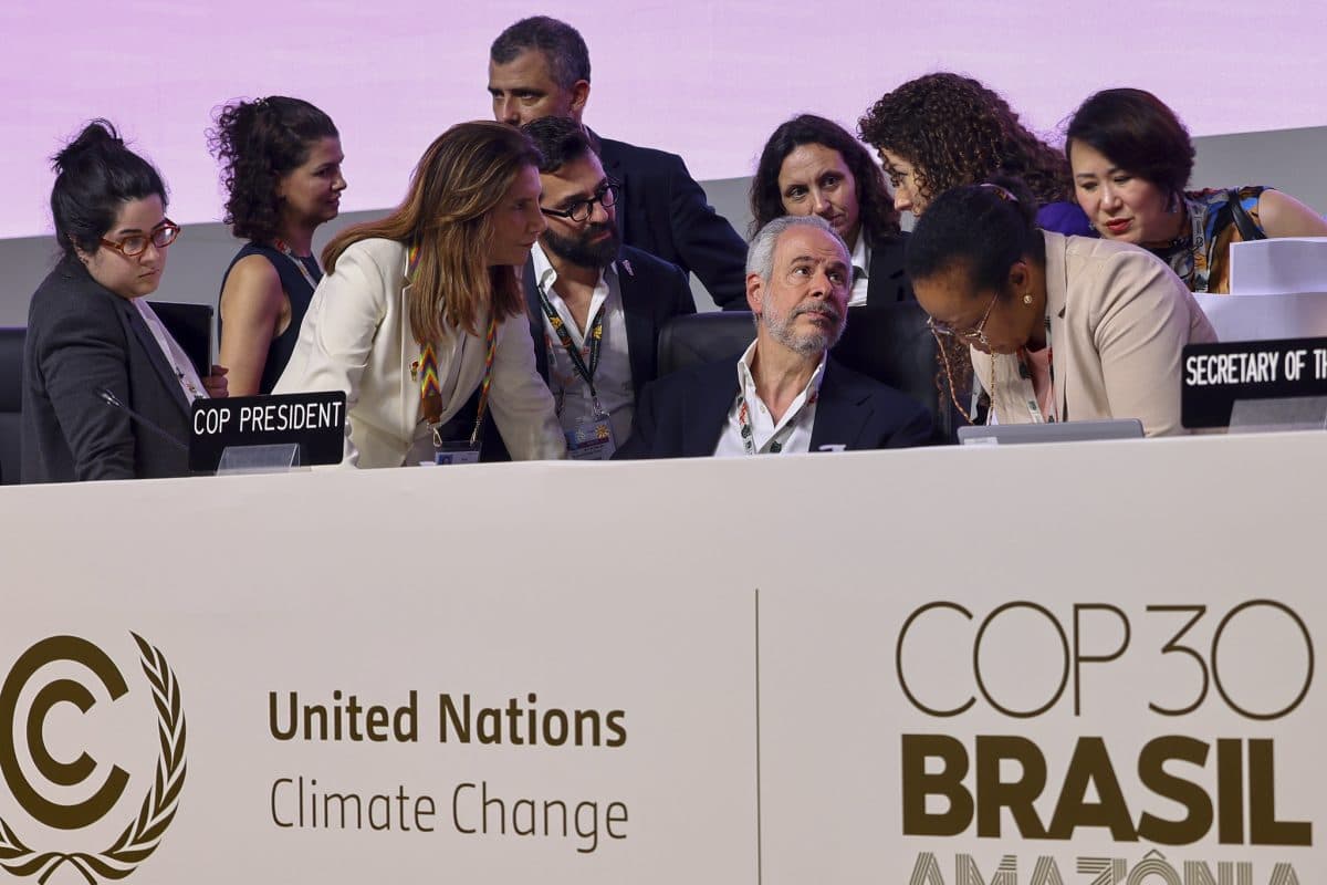 En gruppe tjenestemenn og delegater snakker sammen ved et bord under FNs klimakonferanse COP30 i Brasil.