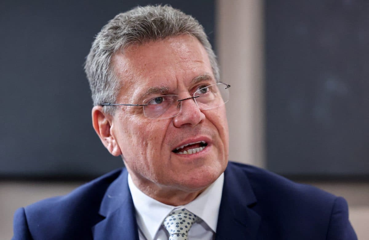 En middelaldrende mann i blå dress, lyseblå skjorte og mønstret slips snakker, han har briller og ser litt til siden.