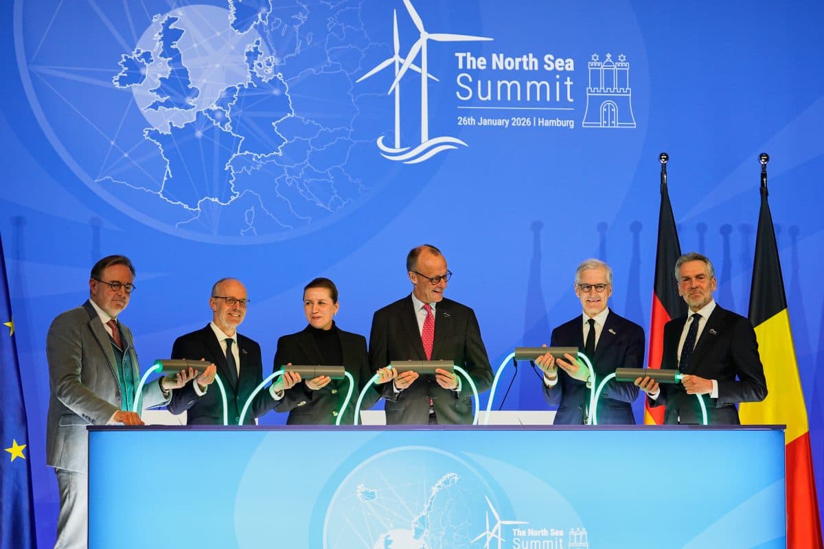 Seks tjenestemenn står bak et opplyst podium med lysende kabler under Nordsjøtoppmøtet 2025 i Hamburg, med europeiske og nasjonale flagg og en toppmøtekulisse bak seg.