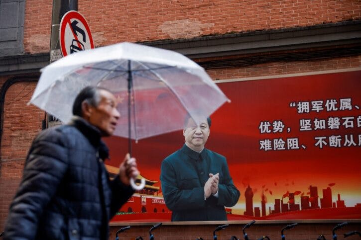 A man walks with an umbrella past a picture of Chinese President Xi Jinping on a street ahead of the National People’s Congress (NPC), in Shanghai
