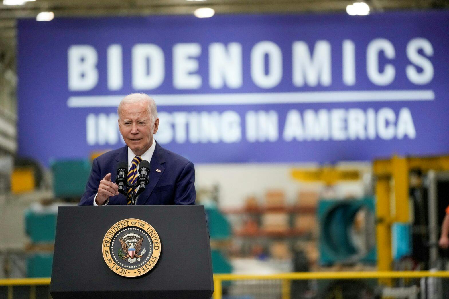 Joe Biden på talerstol, plakat i bakgrunnen med skriften Bidenomics - Investing i America