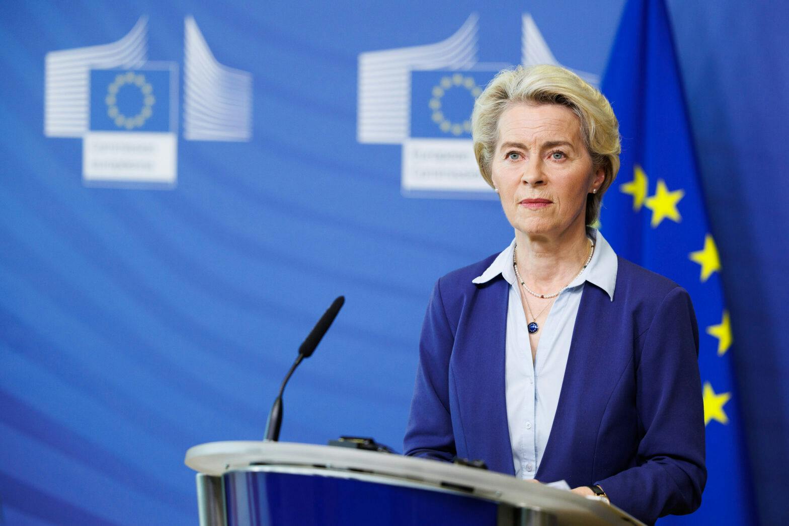 En kvinne som står på et podium foran eu-flagg.