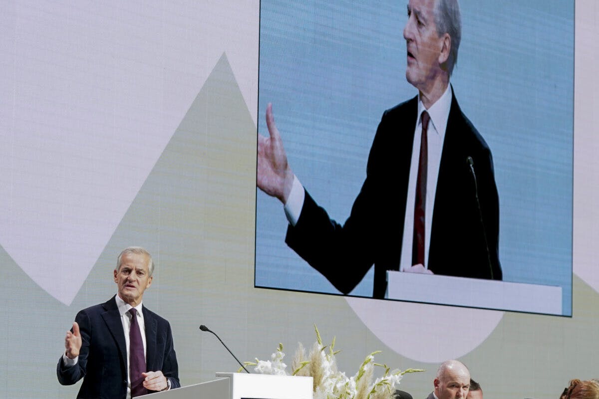 En mann holder en tale foran en stor skjerm.