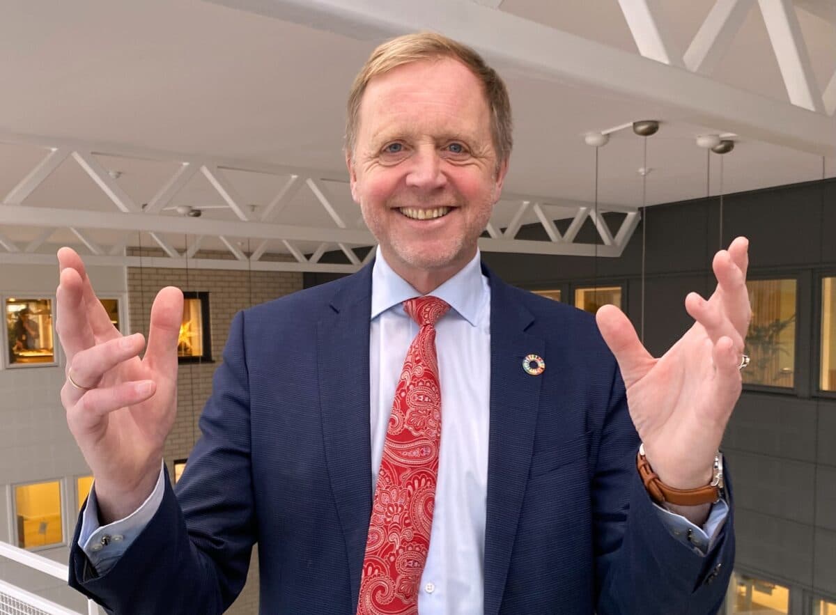 Mann innendørs som strekker ut hendene og åpner dem opp.