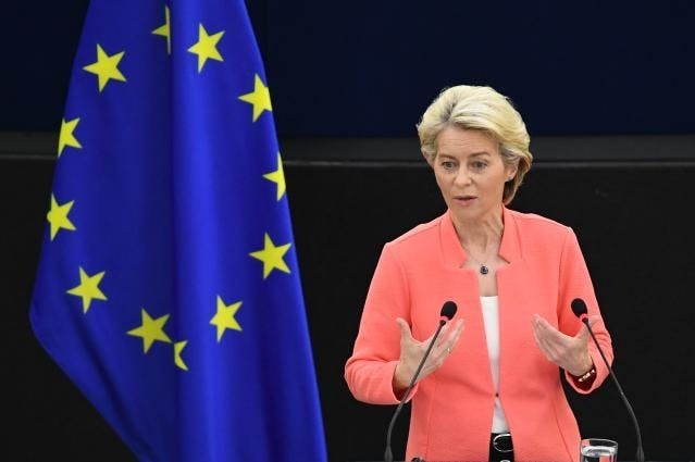 En kvinne holder en tale foran et EU-flagg.