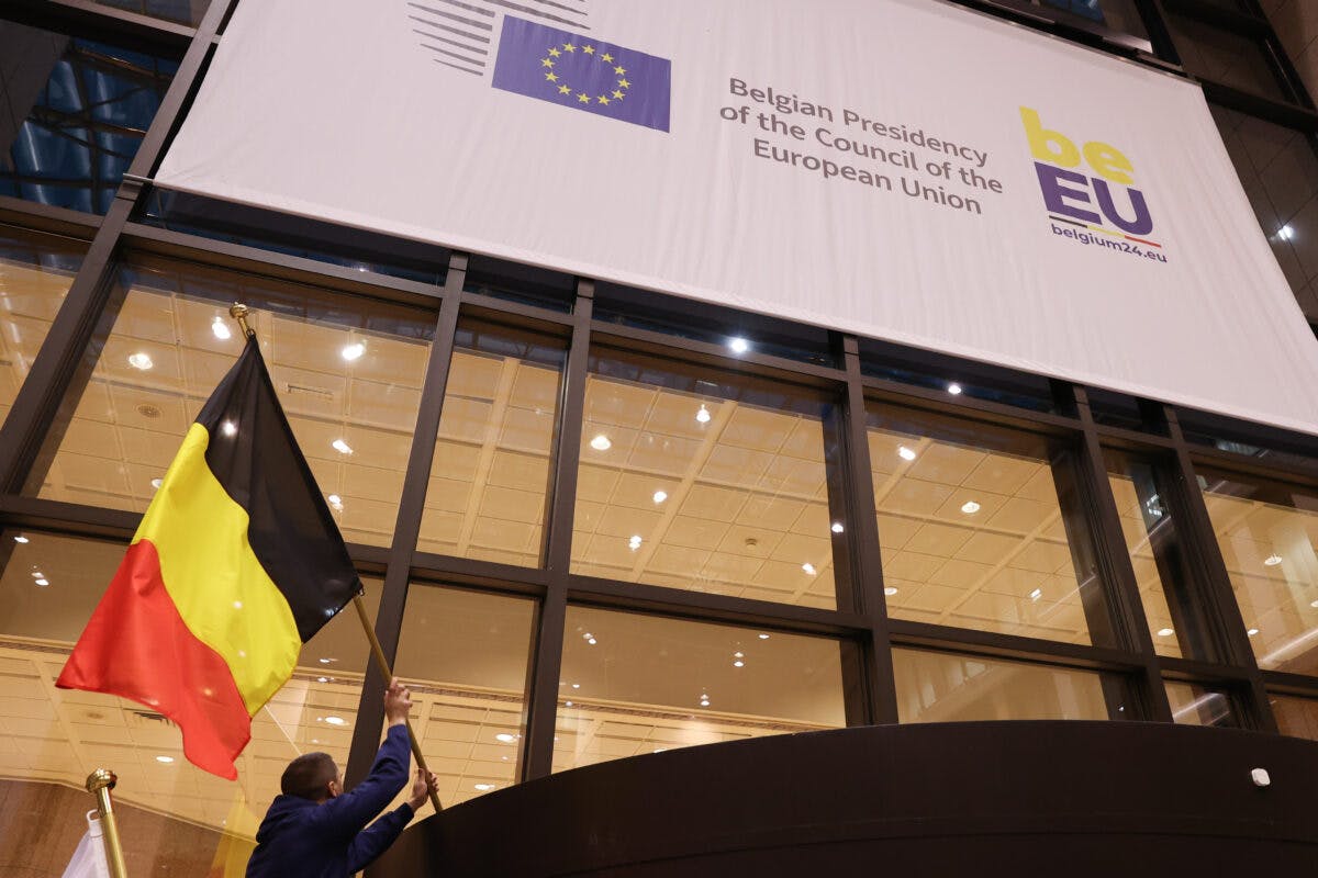 En mann som vifter med et belgisk flagg foran en eu-bygning.