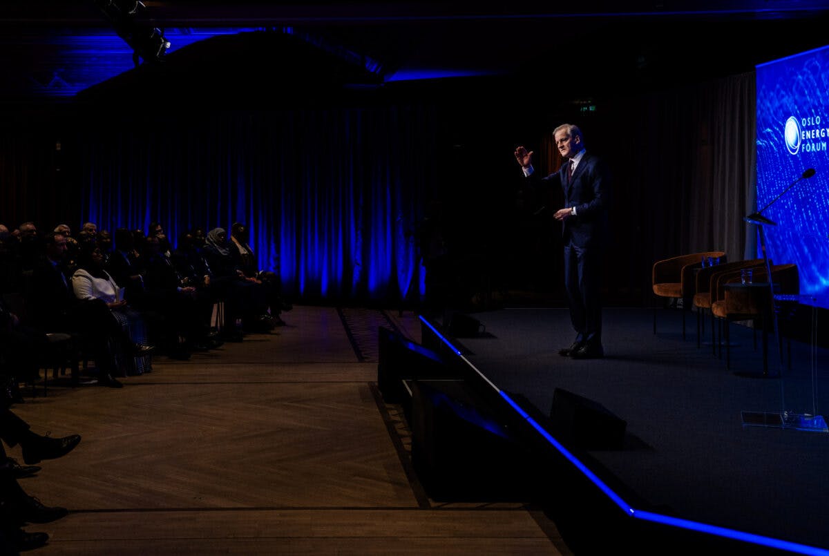 En mann holder en tale på scenen foran et publikum.