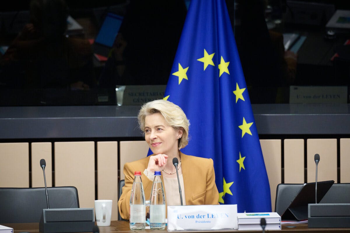 En kvinne som sitter ved et bord foran et EU-flagg.