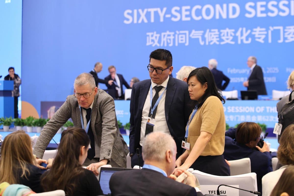 En gruppe mennesker i forretningsantrekk deltar i diskusjon på en konferanse, med "Sixty-Second Session" vist på et blått bakteppe.