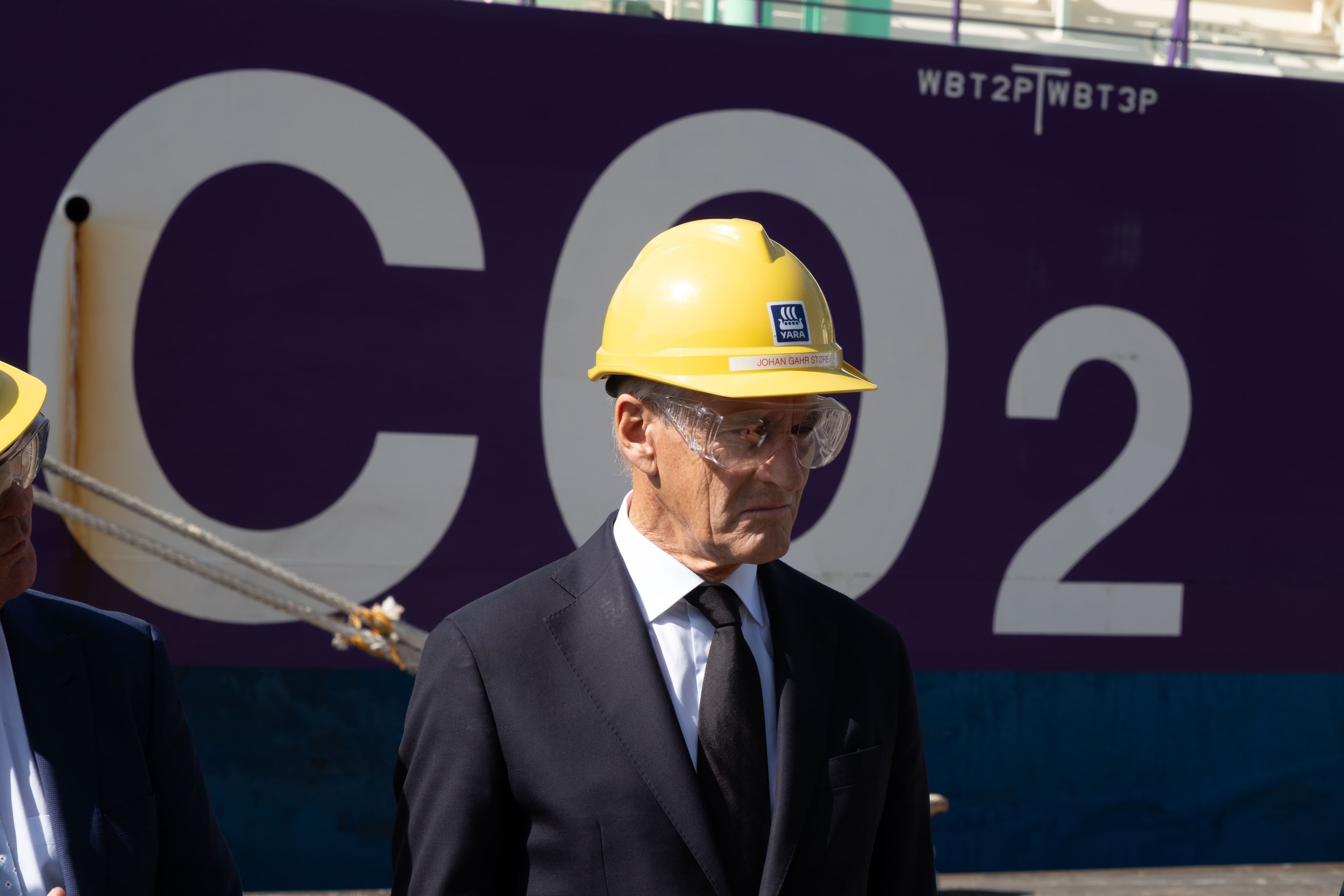 Mann med vernehjelm og vernebriller står foran en lilla flate med «CO2» skrevet med store, hvite bokstaver.