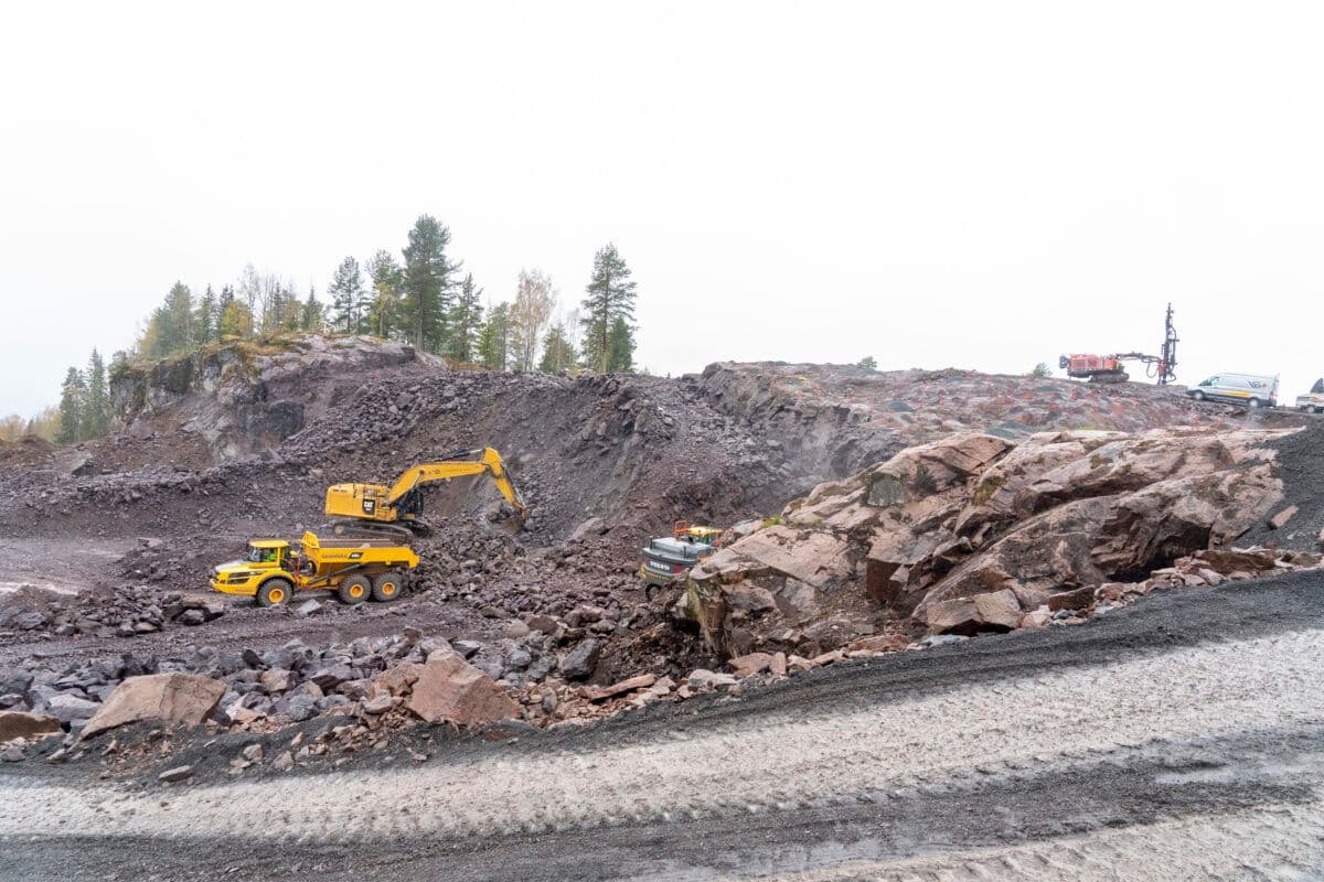 En gravemaskin jobber med en steinrøys.