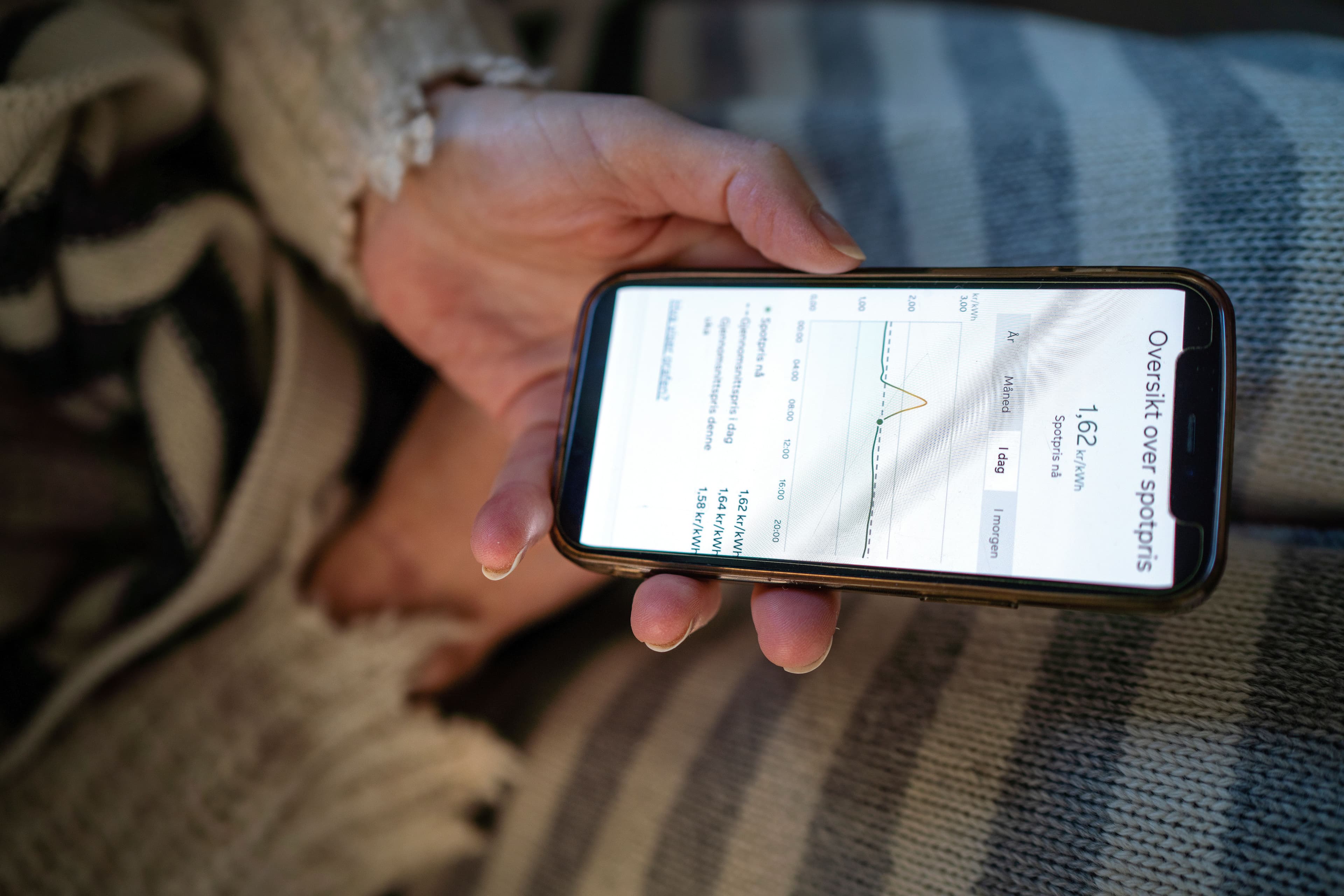 En hånd holder en smarttelefon som viser en graf over spotpriser.