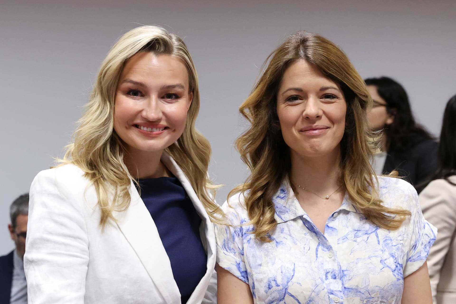 To kvinner, en blondine og en brunette, smiler mot kameraet.