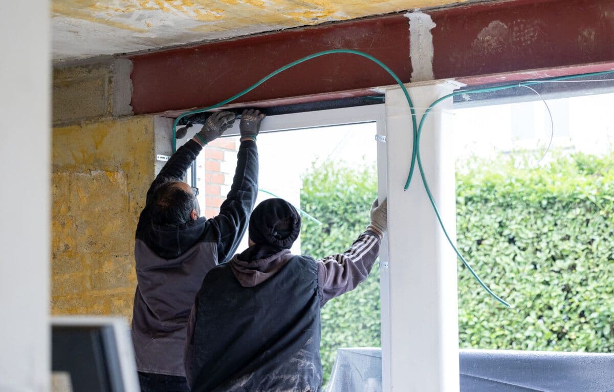 To menn jobber på et vindu i et hus.