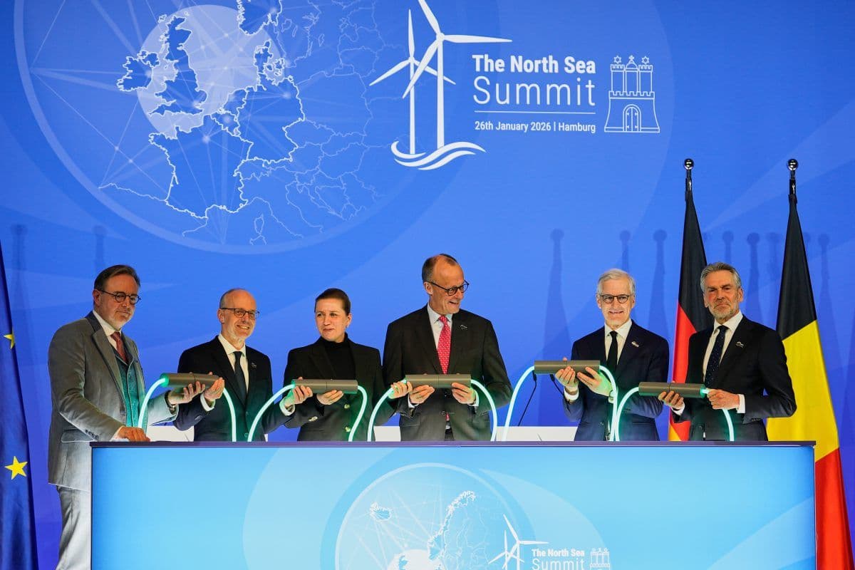 Seks tjenestemenn står bak et opplyst podium med lysende kabler under Nordsjøtoppmøtet 2025 i Hamburg, med europeiske og nasjonale flagg og en toppmøtekulisse bak seg.