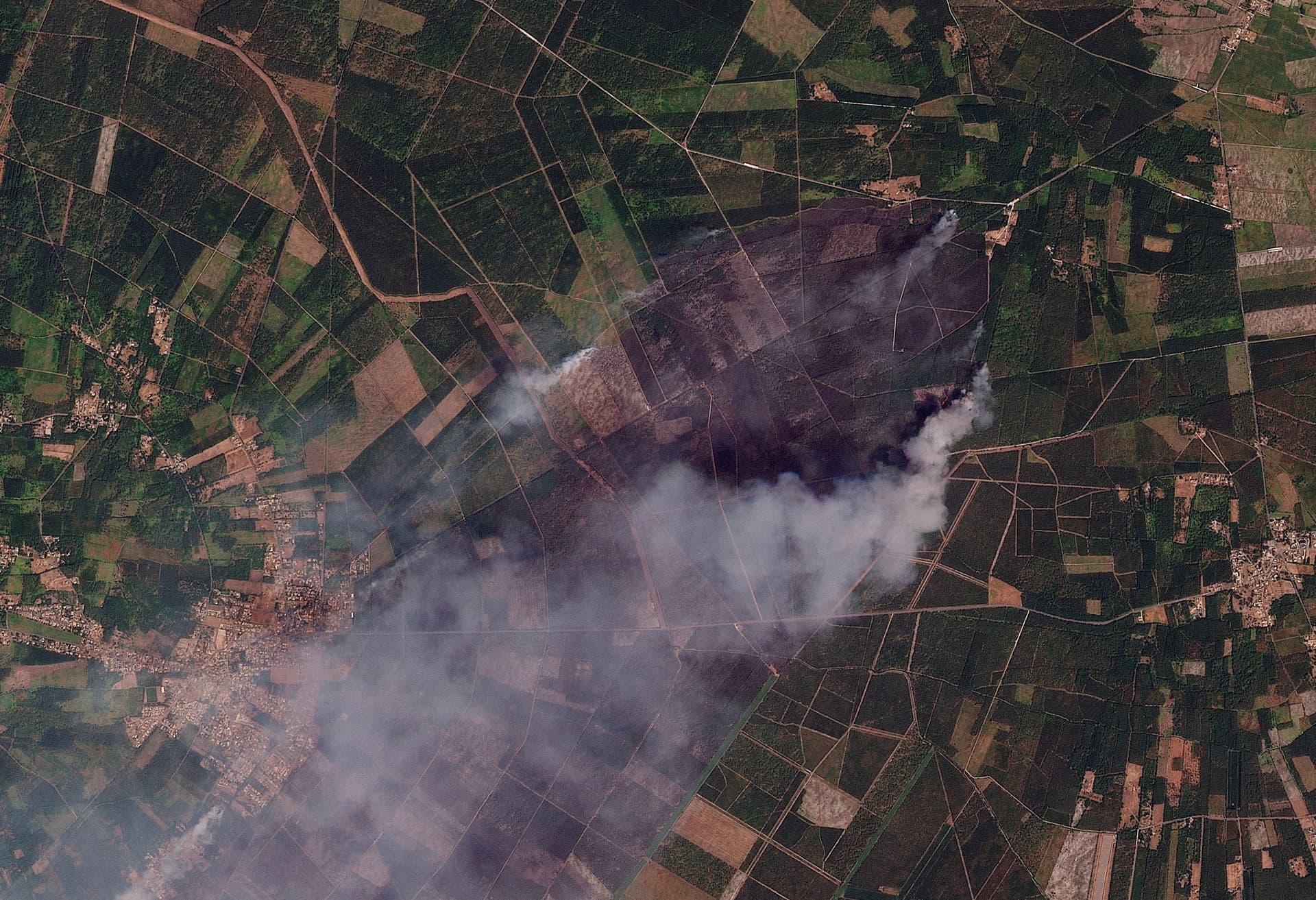 Satellittbilde som viser røyk fra branner over mønstret jordbruksland.