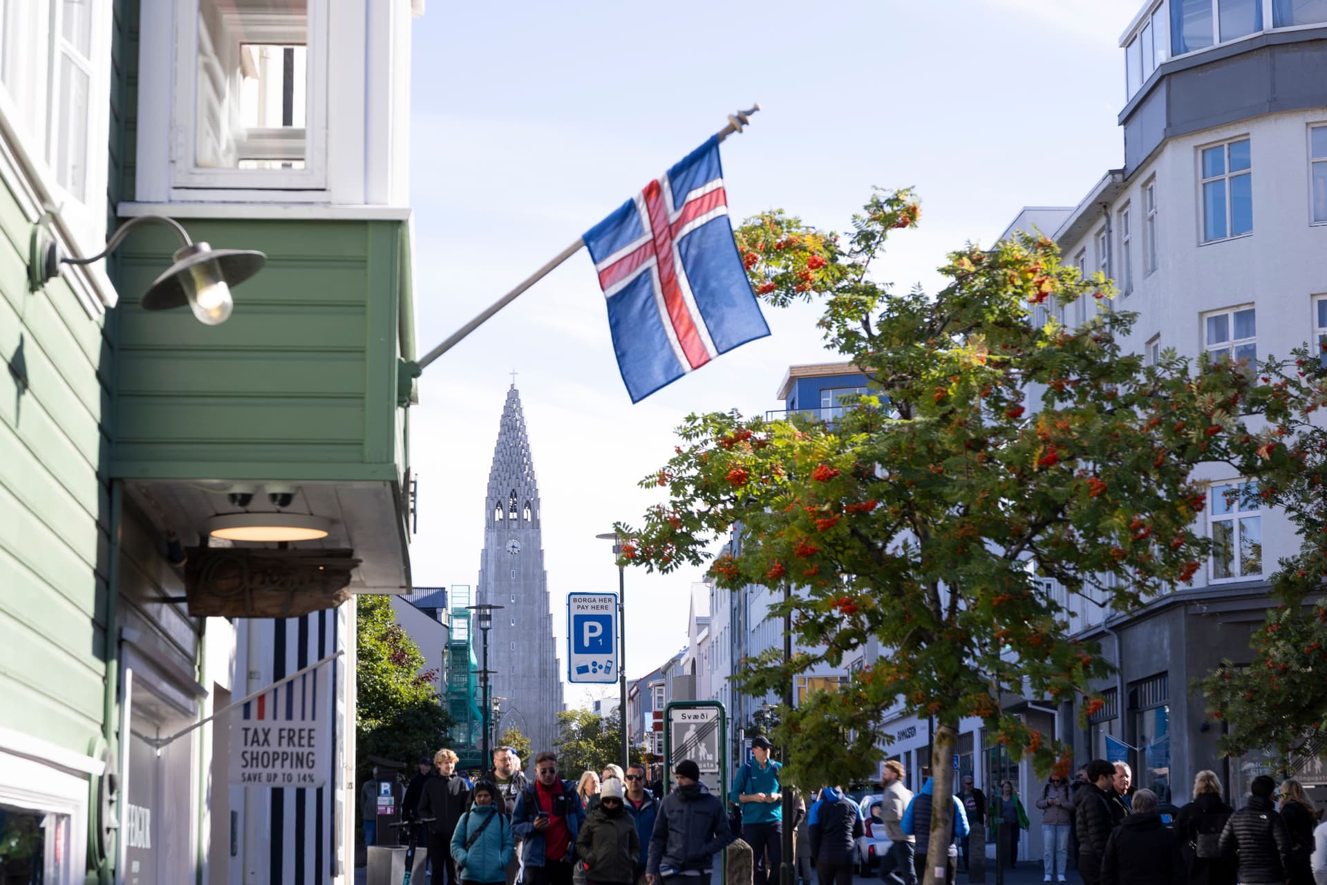 Det islandske flagget vaier over en travel gate i Reykjavík, med spiret på Hallgrímskirkja i bakgrunnen.