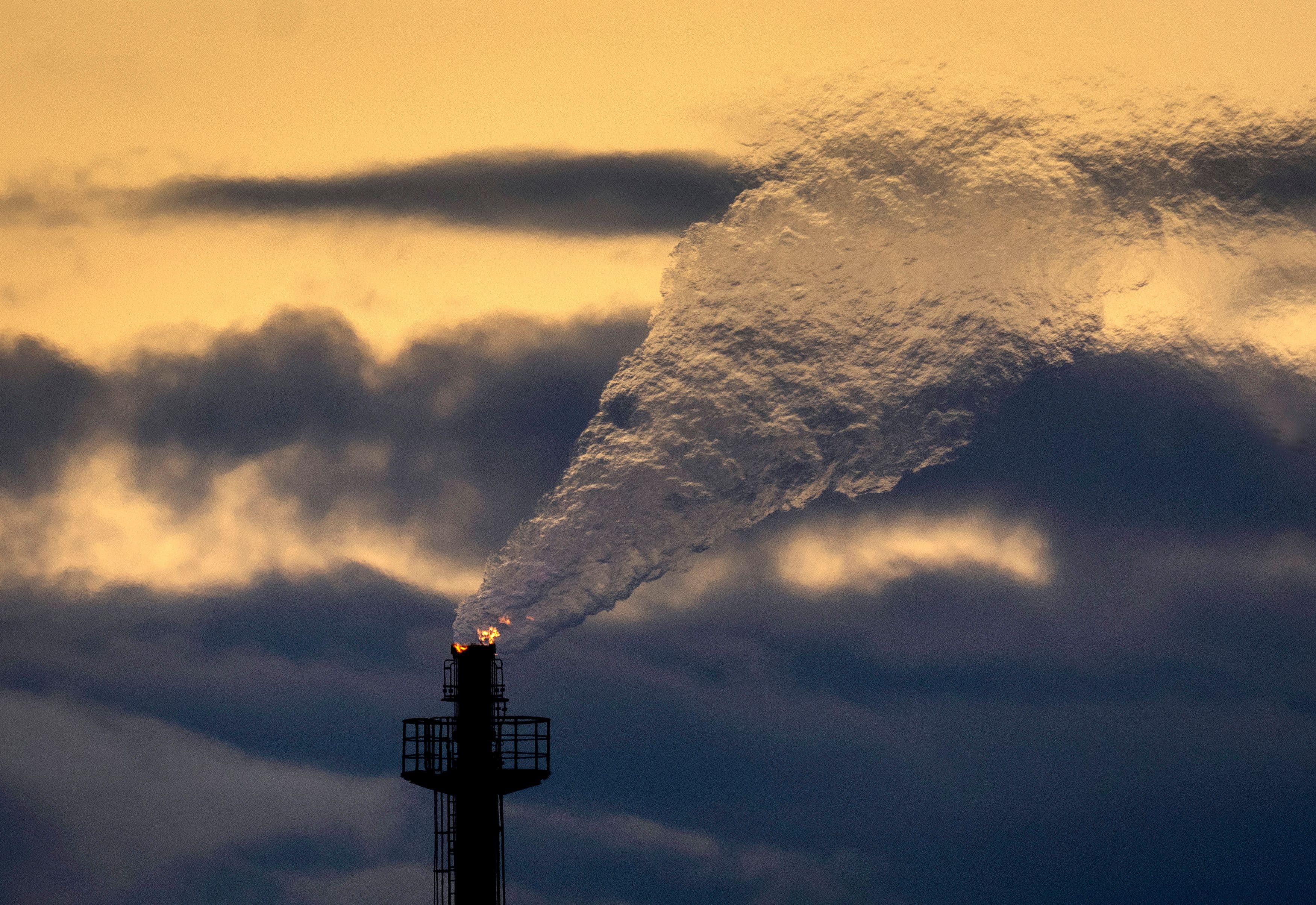 Et tårn slipper ut en stor sky av hvit røyk og flammer mot en mørk, oransjeopplyst himmel.