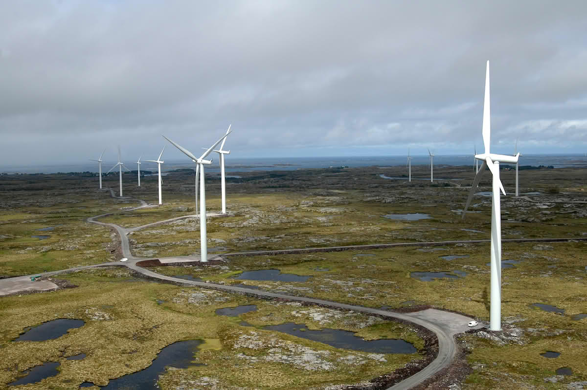 Vindpark i et steinete, myrlendt landskap med svingete veier og små tjern.