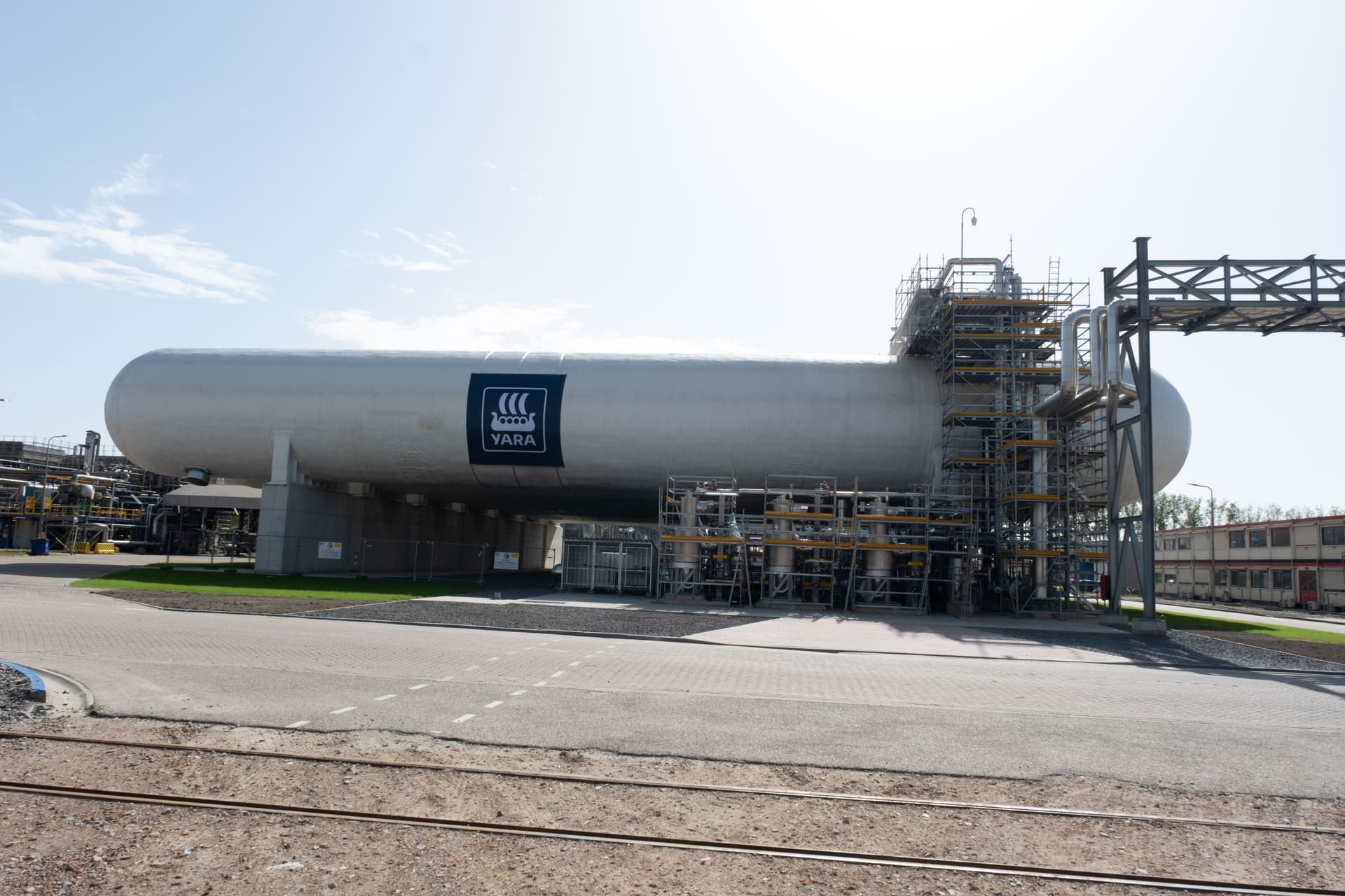 A large horizontal YARA storage tank with scaffolding at one end in an industrial facility.
