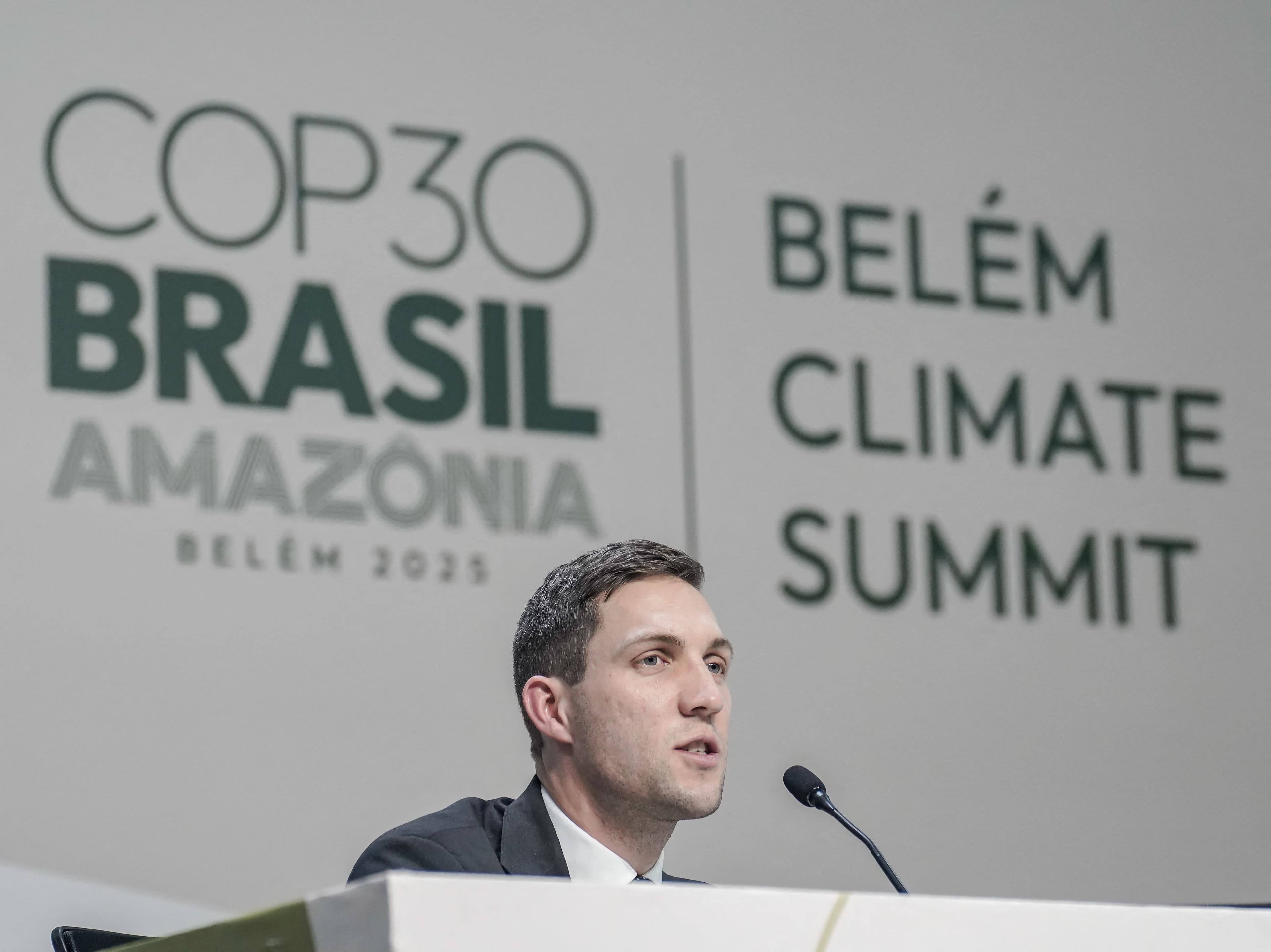 Mann som taler fra en talerstol foran en stor bakvegg med teksten «COP30 Brasil Amazônia» og «Belém Climate Summit».