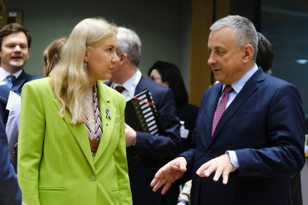 To personer i profesjonelt antrekk i samtale på et arrangement, med kvinnen kledd i en knallgrønn blazer som lyttet oppmerksomt til mannen som gestikulerte med hendene.