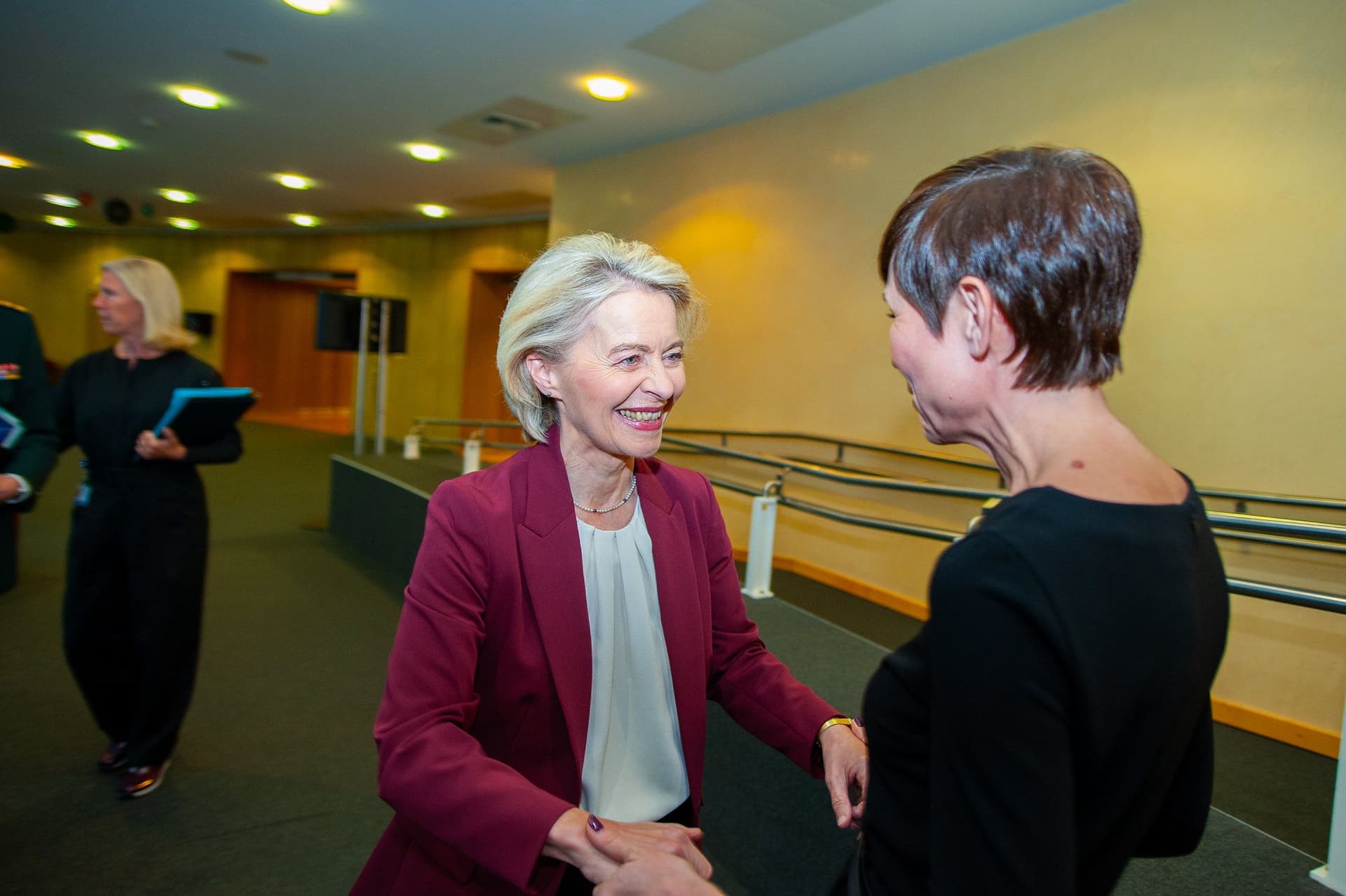 Ursula von der Leyen, smilende i en rød blazer, håndhilser på Ine Eriksen Søreide.