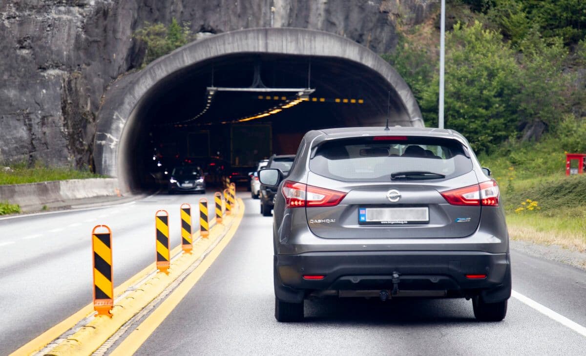 En bil som kjører nedover en vei nær en tunnel.
