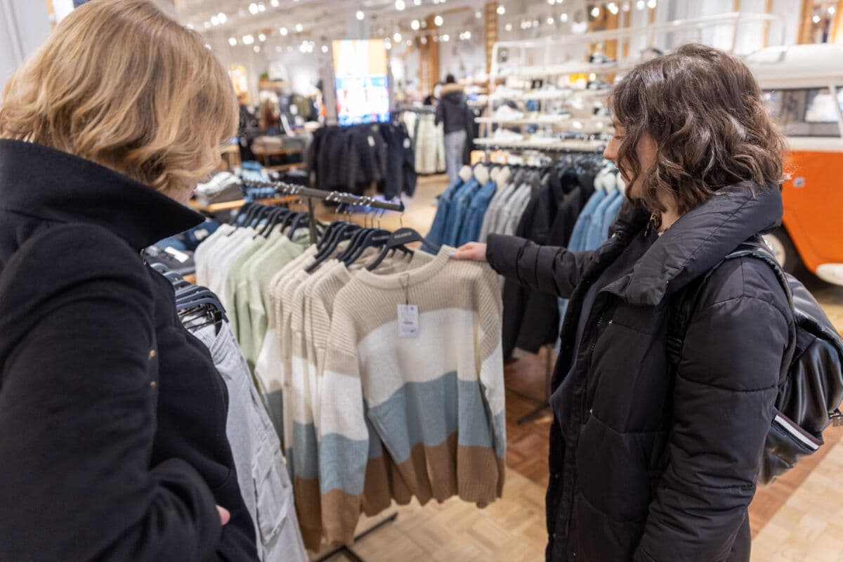 To kvinner ser på klær i en klesbutikk.