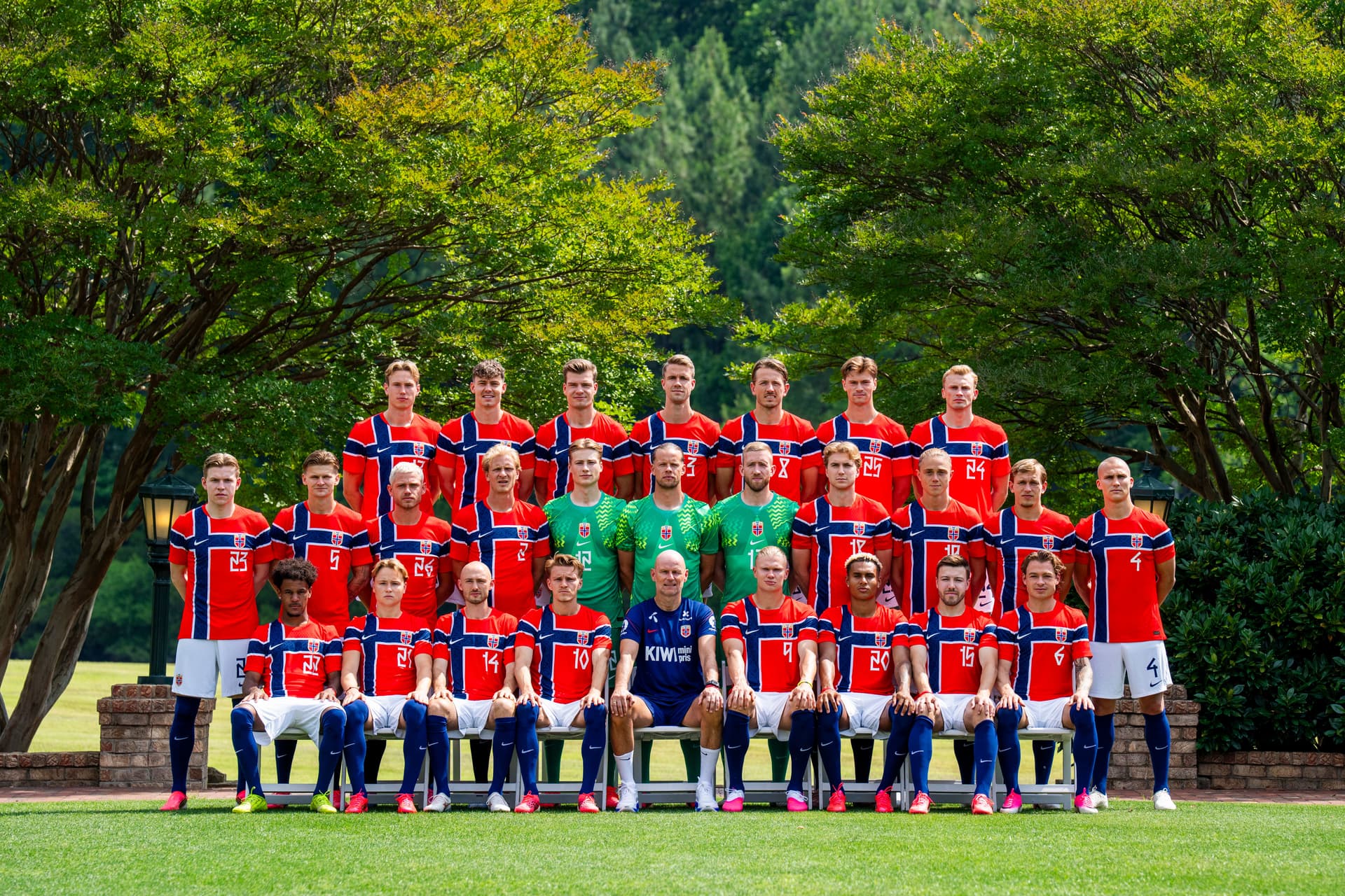 A group photo of the Norwegian men's soccer team and their coach on a grassy field.