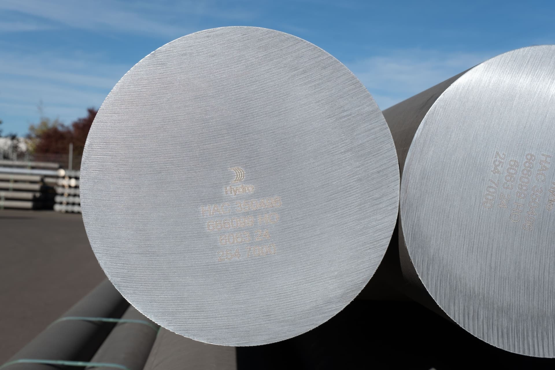 Nærbilde av endene på to store, sølvfargede metallsylindere, inngravert med Hydro-logoen og produktdetaljer.