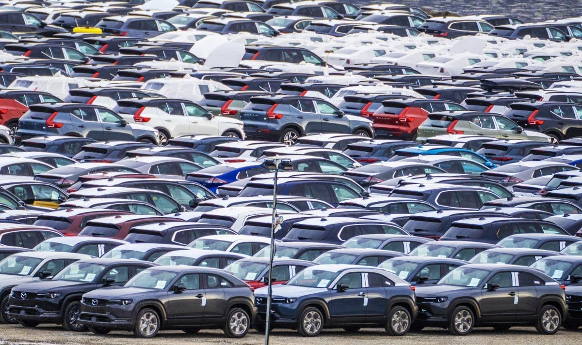 Stor parkeringsplass fylt med rader av parkerte biler, for det meste SUV-er i ulike farger, plassert tett i tett.