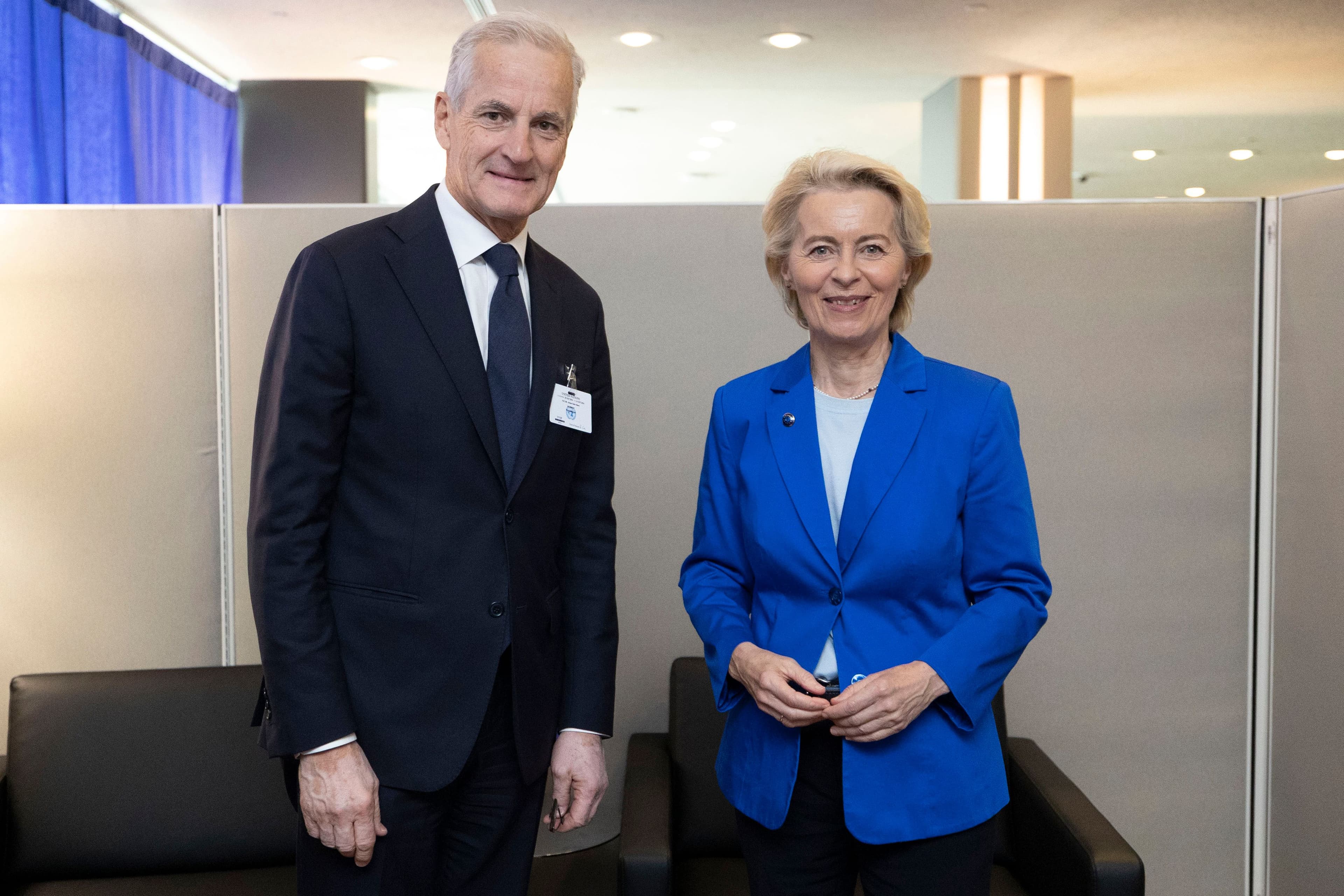 Ursula von der Leyen in a blue blazer and a man in a dark suit stand smiling.