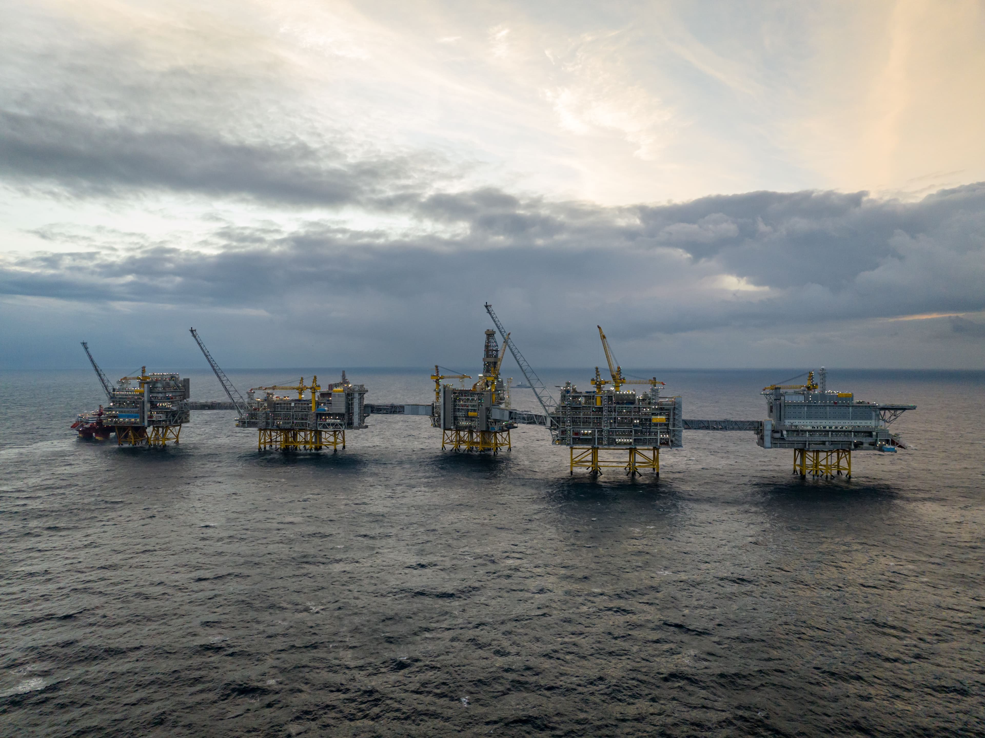 Et offshore olje- og gassplattformkompleks ute i havet under en skyet himmel.