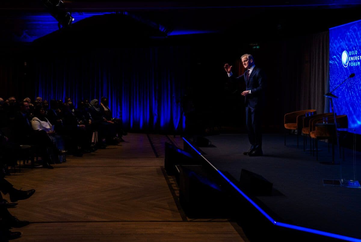 En mann holder en tale på scenen foran et publikum.