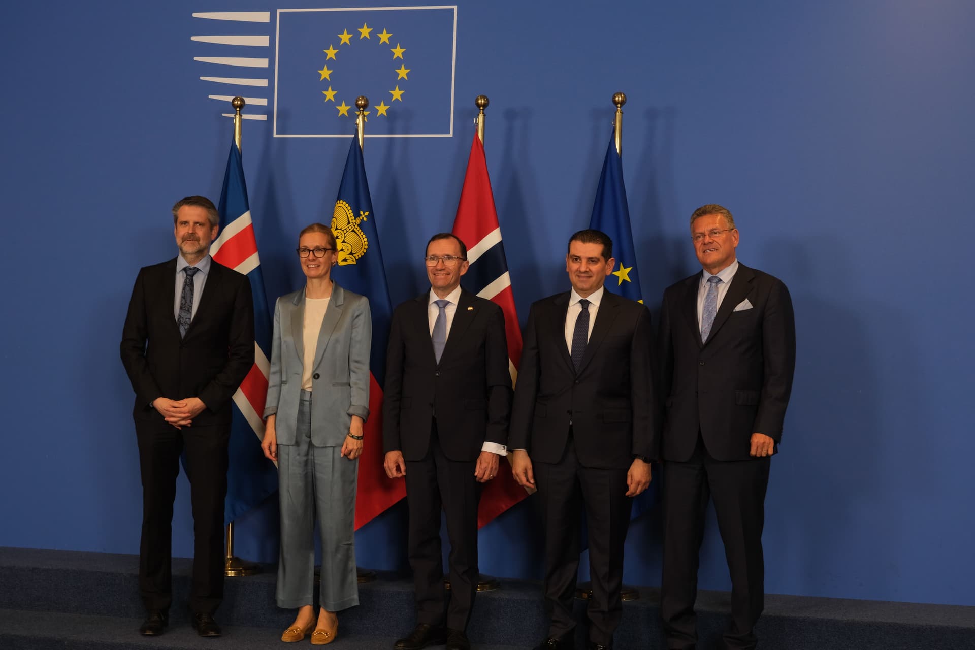 Fem personer i businessantrekk står foran flaggene til Island, Liechtenstein, Norge og EU-emblemet.