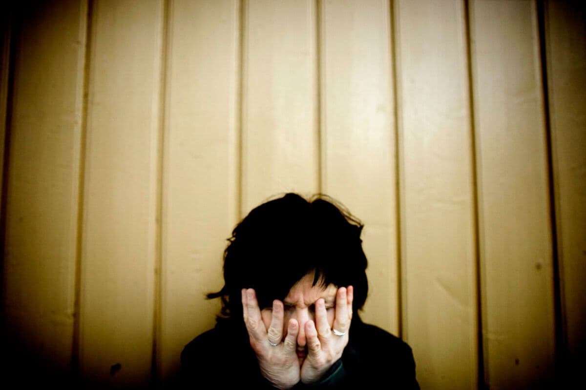 En kvinne som dekker ansiktet med hendene.