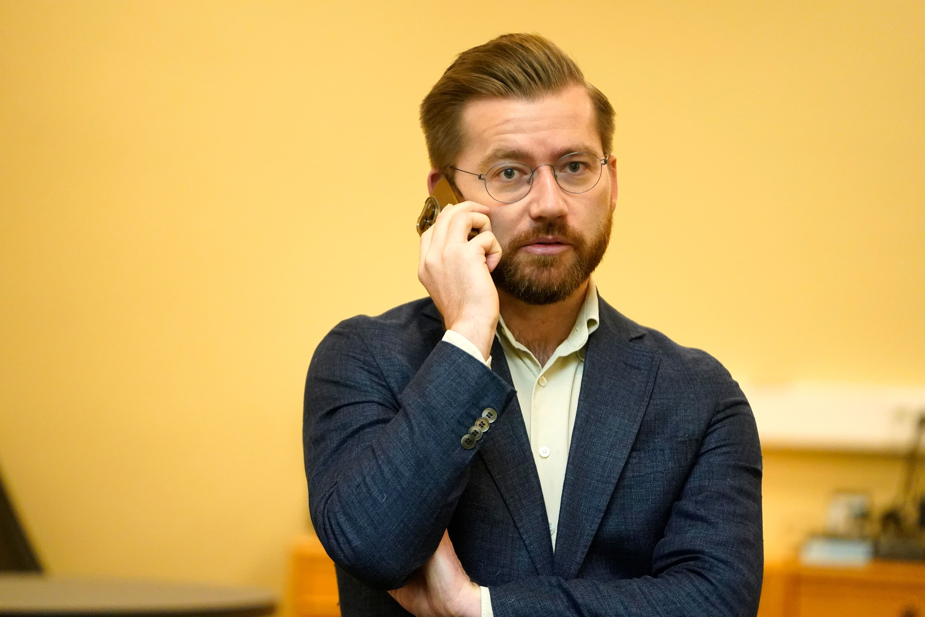 En skjeggete mann med briller snakker i mobiltelefon.