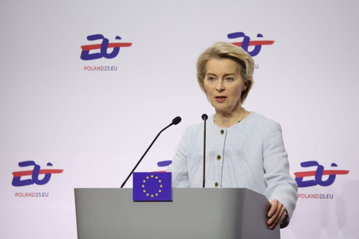 En kvinne står på et podium med EU-flagget og snakker i flere mikrofoner. Bakgrunnen har en logo med "POLAND25.EU.