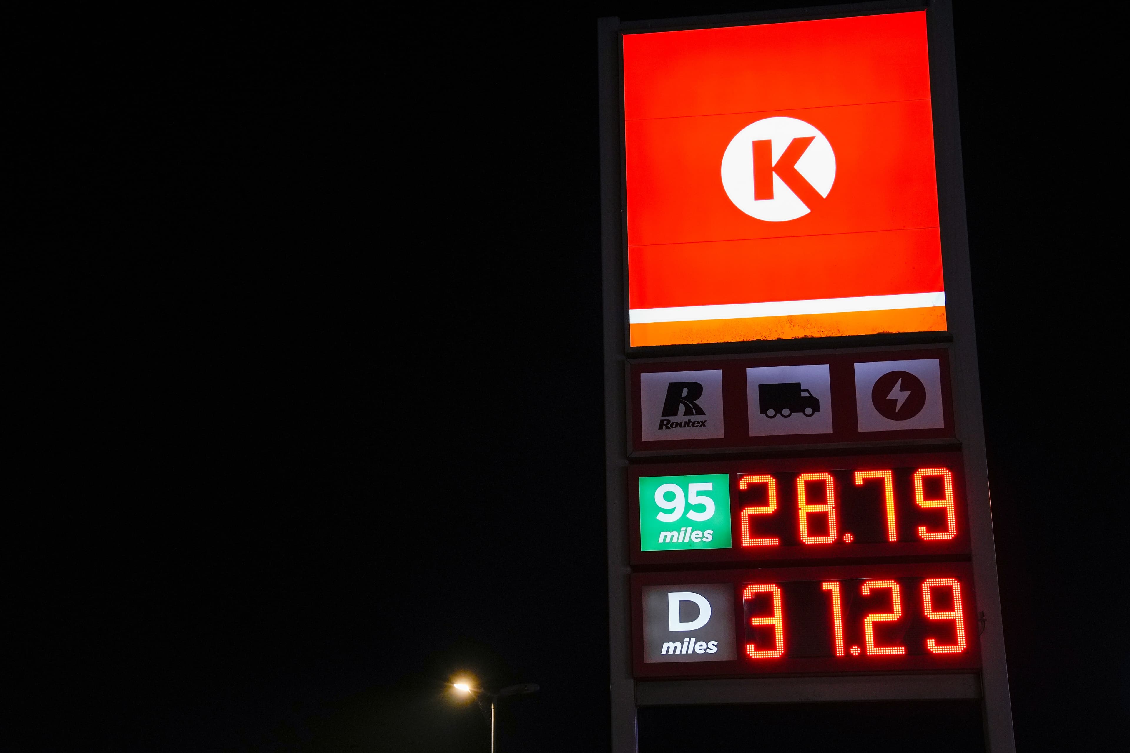 Et Circle K-bensinstasjonsskilt om natten som viser priser: 95 miles for 28,79 og D miles for 3,129.