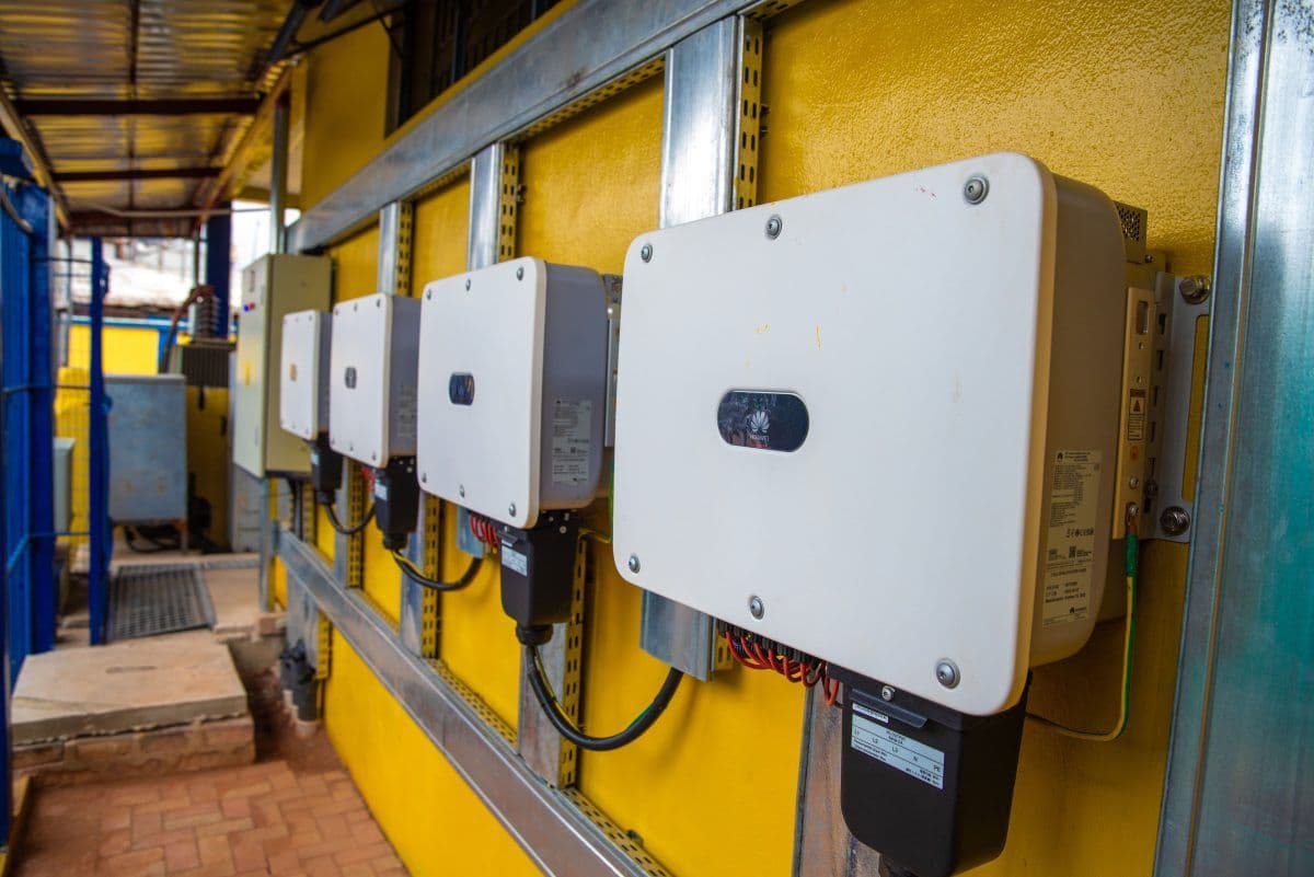 En rekke hvite omformerbokser montert på en gul vegg, med kabler koblet til hver enhet i et utendørs miljø.