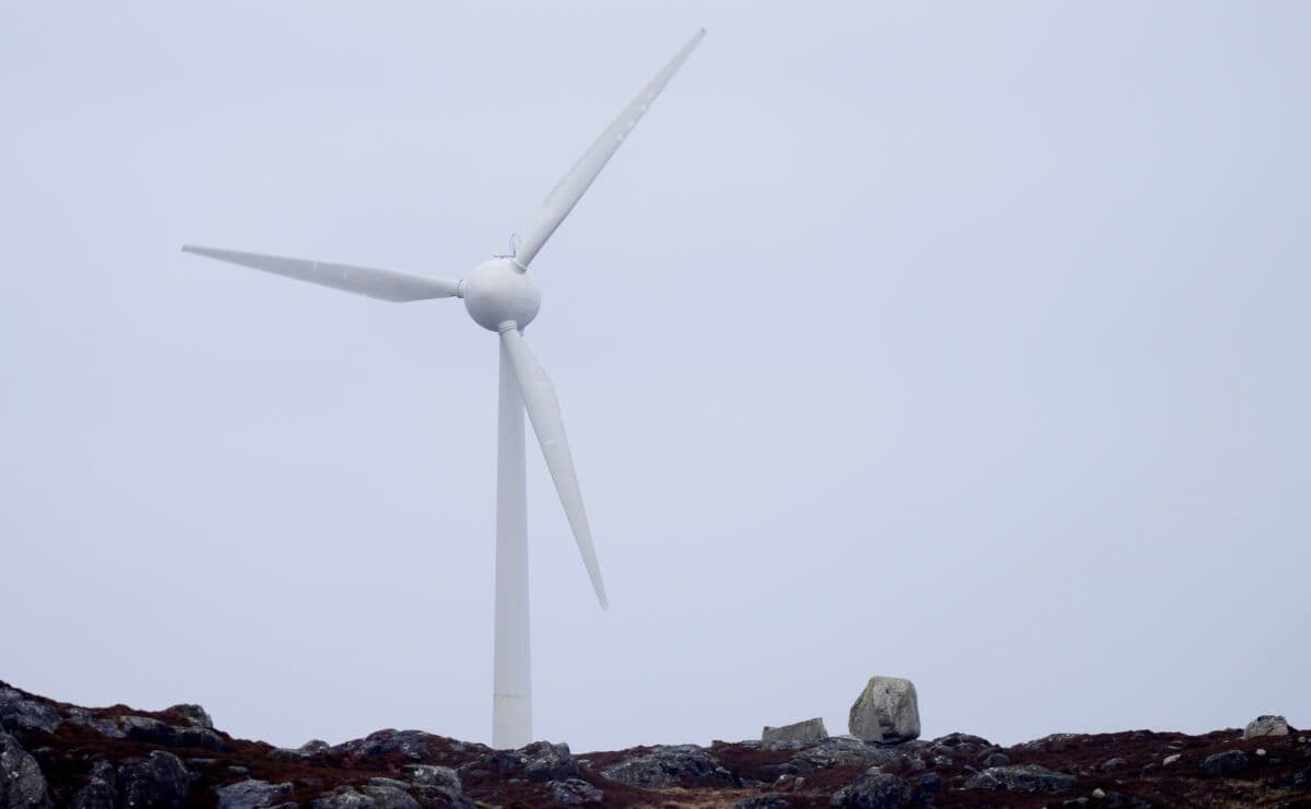 En vindturbin sitter på toppen av en steinete bakke.