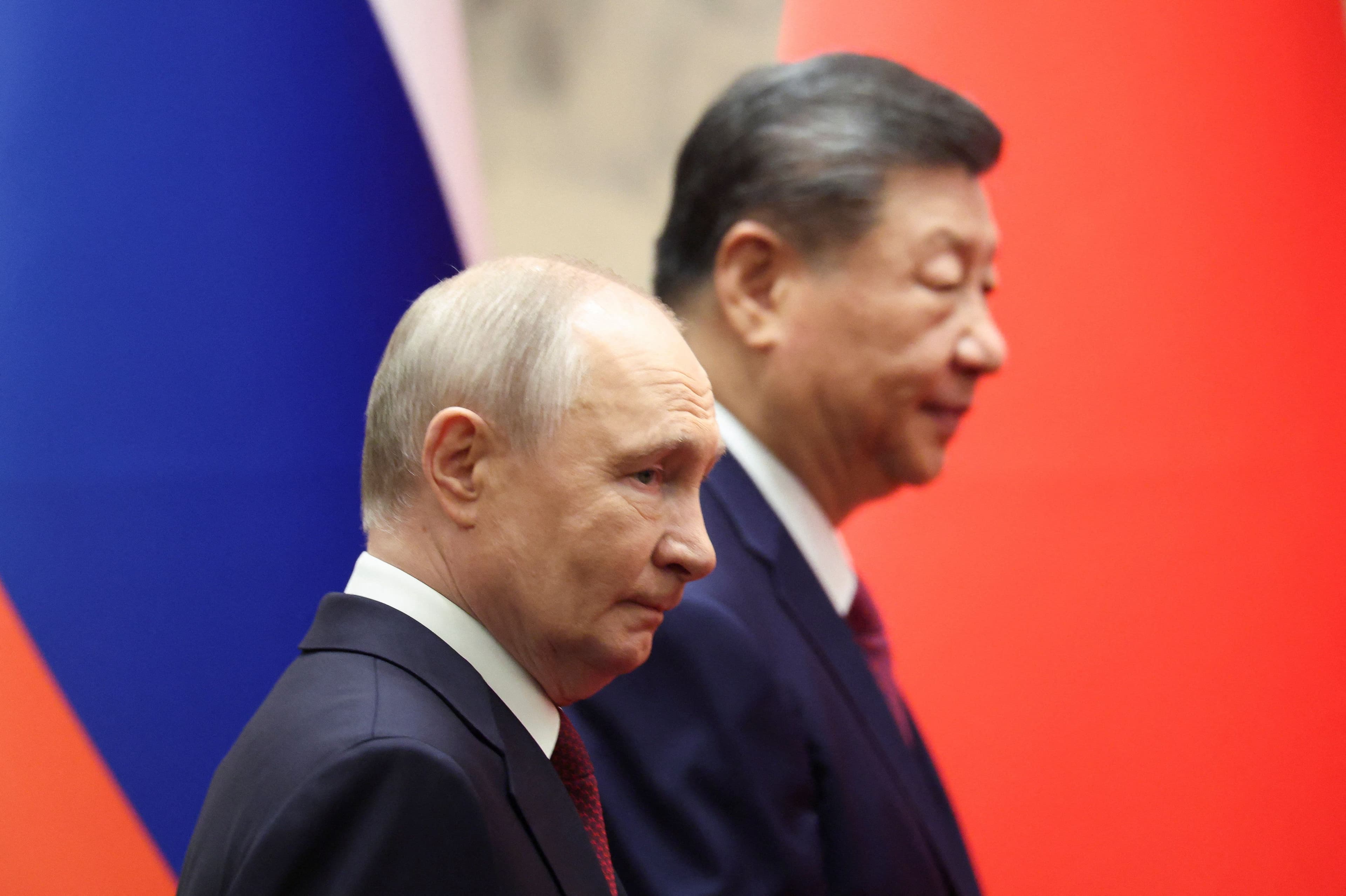 Russlands president Vladimir Putin ser betenkt ut, Kinas president Xi Jinping i bakgrunnen.