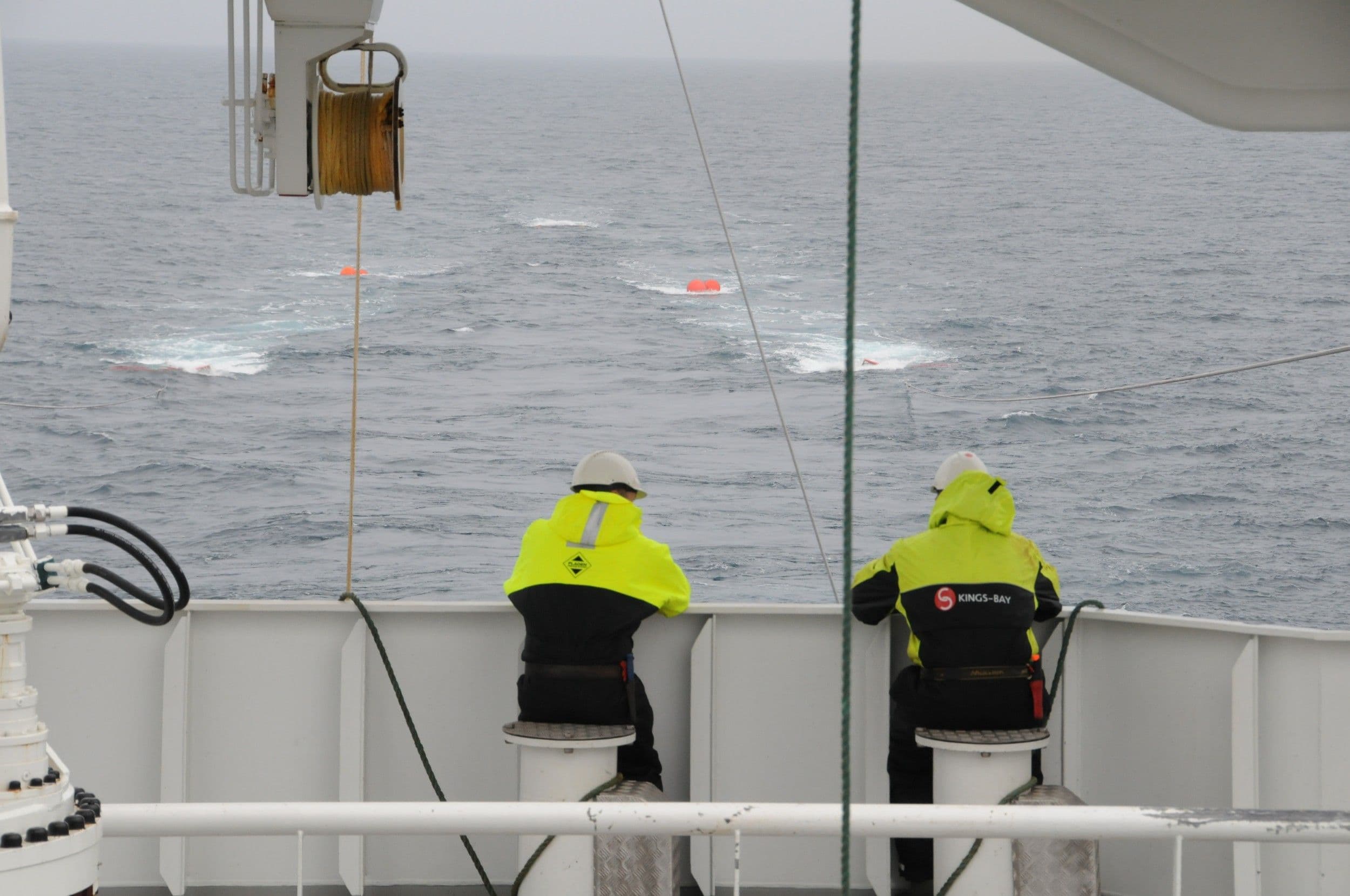 To menn lener seg på rekka på et skip og ser utover havet